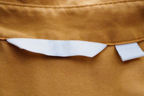 Fehér üres ruházat címke barna ing háttér - Fotó, kép