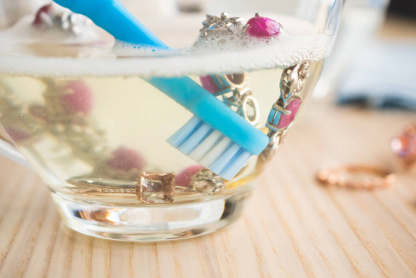 puhdistus vintage koruja timantti rengas ja rannekoru lasi kuumaa vettä ja astianpesunestettä puupöydällä tausta - Valokuva, kuva