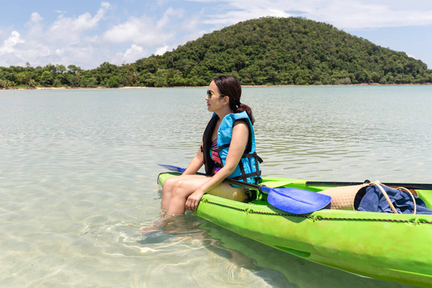Turista mujer sentada en kayak lookign en hermosa playa tropical de vacaciones - Foto, imagen