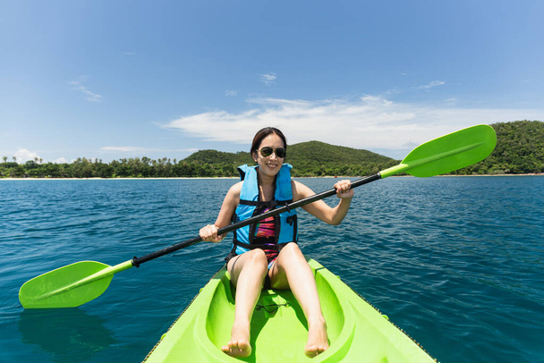 Happy woman with lifejacket kayaking in tropical island ocean on vacation - Photo, Image