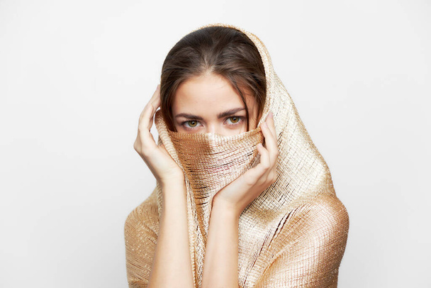 Una chica en una bufanda de oro cubre la cara étnica religión maquillaje  - Foto, Imagen