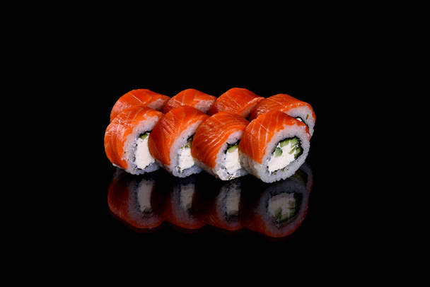 Frescos y deliciosos rollos de sushi sobre un fondo oscuro. Elementos de la cocina japonesa - Foto, Imagen