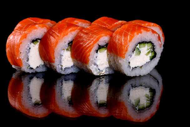 Frescos y deliciosos rollos de sushi sobre un fondo oscuro. Elementos de la cocina japonesa - Foto, imagen