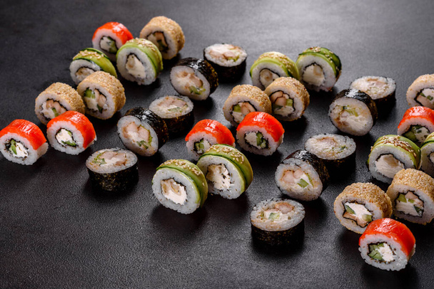 De délicieux sushis frais et délicieux roulent sur un fond sombre. Éléments de la cuisine japonaise - Photo, image