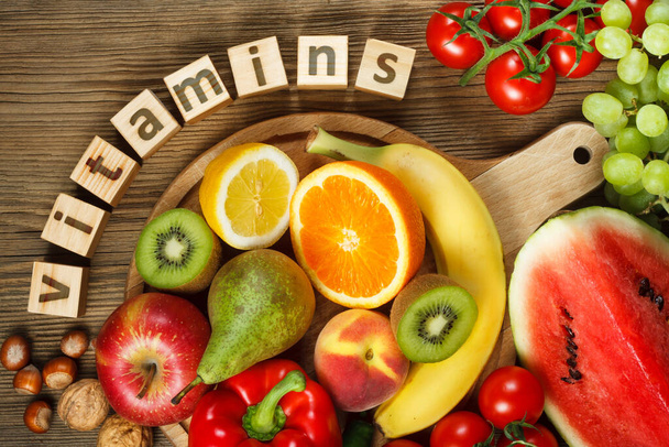 Витамины в фруктах и овощах. Натуральные продукты, богатые витаминами, как апельсины, лимоны, красный перец, киви, помидоры, бананы, груши, яблоки, грецкие орехи, арбузы, фундук, персик и зеленый виноград - Фото, изображение