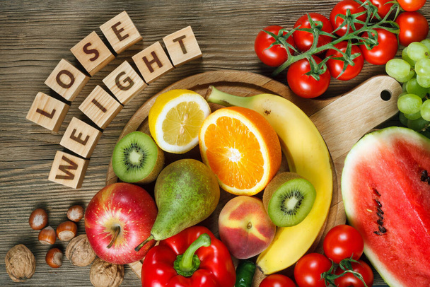 Diétás fogalom. Vitaminokban gazdag természetes termékek: narancs, citrom, pirospaprika, kivi, paradicsom, banán, körte, alma, dió, görögdinnye, mogyoró, őszibarack és zöld szőlő - Fotó, kép