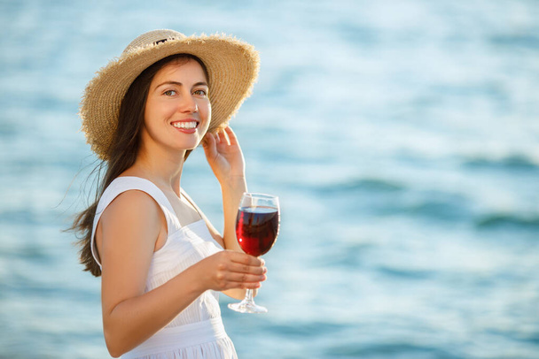 mujer sosteniendo copa de vino junto al mar - Foto, imagen