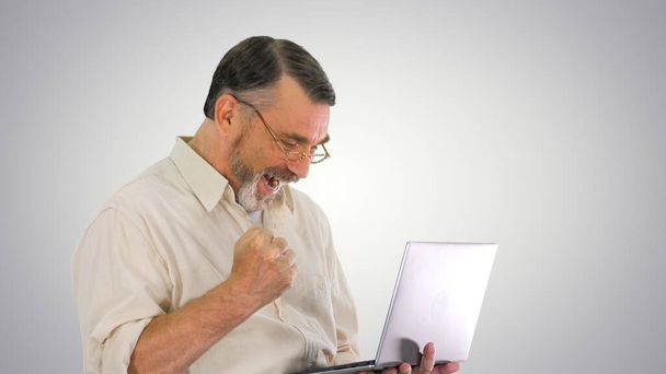 Podekscytowany starszy biznesmen pracujący nad laptopem na gradiencie pleców - Zdjęcie, obraz