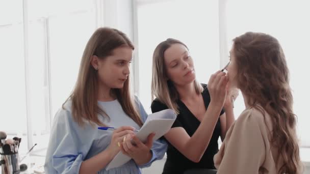 Adult professional teacher visagiste training her student to become makeup artist at master class in beauty salon. - Footage, Video