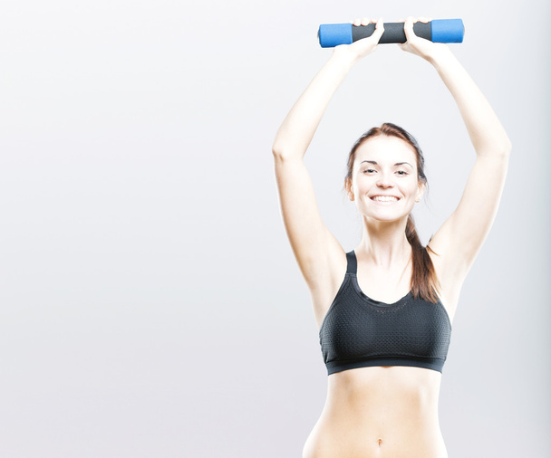 Mujer sonriente en forma durante el ejercicio con mancuerna
 - Foto, imagen