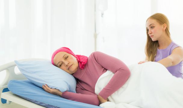 Молода доросла пацієнтка з раком жінки проводить час з обіймами дочки в ліжку в лікарні. концепція підтримки сім'ї
. - Фото, зображення