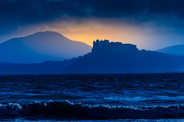 イタリアのカンパニア州プロシダ島。夕暮れと夢のような雰囲気と雰囲気のビーチから見た城のシルエットと夕日の島のイメージ. - 写真・画像