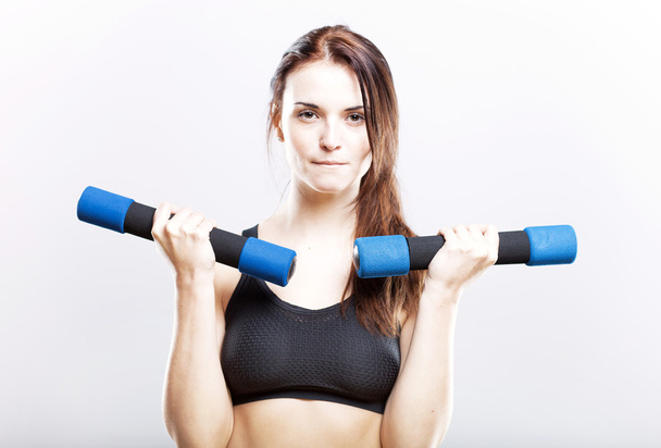 Fit woman during exercise with dumbbells - Photo, image
