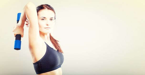 Young fit woman in sport bra during exercise with dumbbells - Fotó, kép