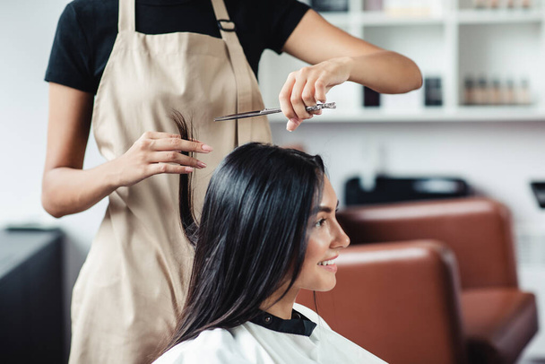 Close up portrait of happy woman getting cut of split ends at hairdressers - Photo, Image