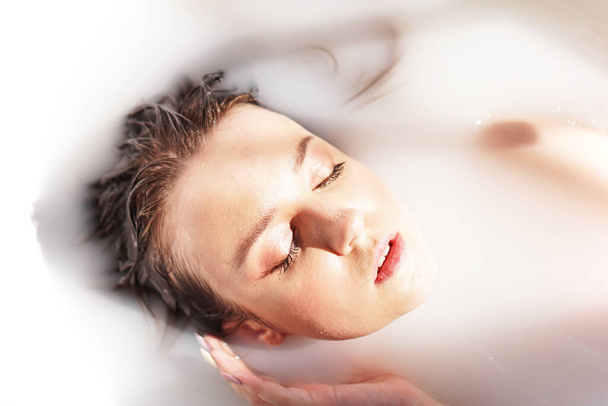 Attractive girl in bath with milk. Spa treatments for skin rejuvenation. - Foto, Bild