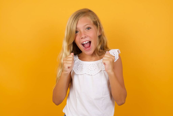 cute  girl  with fists  on yellow background  - Photo, Image