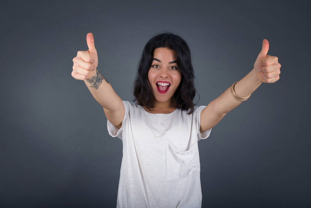 Good job! Portrait of a happy smiling  young successful woman giving two thumbs up gesture standing indoors. Positive human emotion facial expression body language. Funny girl - Fotó, kép