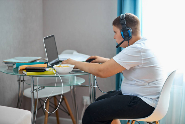 fat teenager boy eat junk food and play computer games - Photo, Image