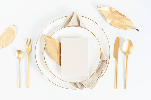 Natale festivo, matrimonio, tavola di compleanno con posate dorate e piatto di porcellana. Mockup della carta bianca. Modello di menu del ristorante. Posa piatta, vista dall'alto - Foto, immagini