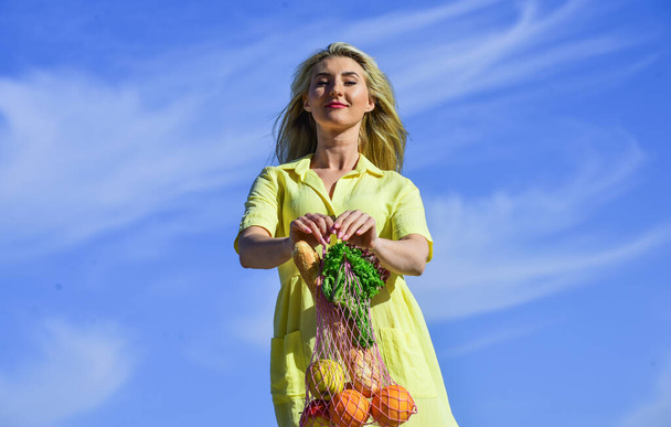 girl go shopping. enjoy summer weather. healthy lifestyle. care your health. fitness and dieting. organic food only. woman carry apple orange salad and bread in string bag. Unhealthy vs healthy food - 写真・画像