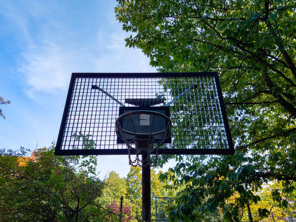 Ein Basketballkorb auf einem Spielplatz mit Bäumen im Hintergrund - Foto, Bild
