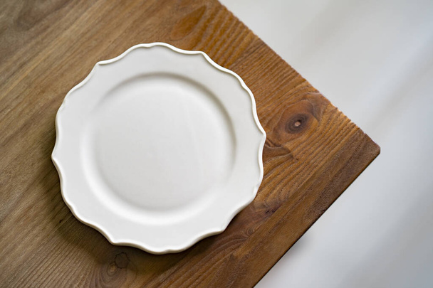 a simple ceramic plate placed on a wooden dining table - Valokuva, kuva