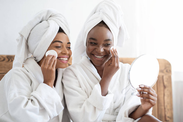 Namoradas atraentes aplicando toner rosto com almofadas, olhando para o espelho - Foto, Imagem
