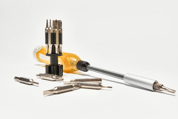 Screwdriver with a universal set of bits, on a light background - Photo, Image