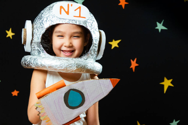 Πορτρέτο ενός χαριτωμένου μικρού κοριτσιού Aisan, χώρος στο σπίτι, όνειρα και παίζοντας αστροναύτη. Αστείες οικογενειακές στιγμές - Φωτογραφία, εικόνα