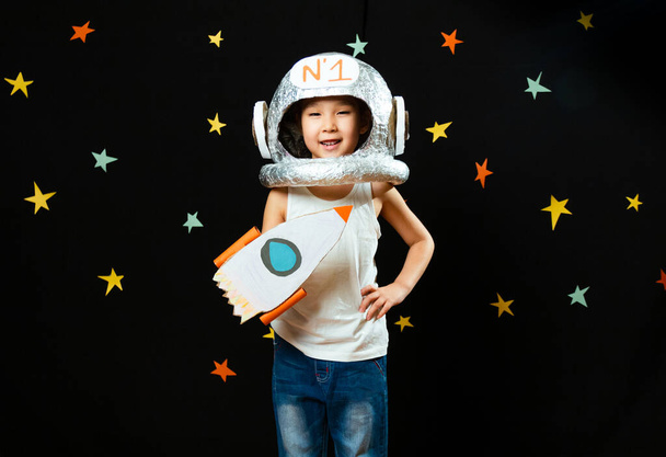 Portret uroczej Aisańskiej dziewczynki, przestrzeń w domu, marzenie i zabawa w astronautę. Zabawne chwile rodzinne. - Zdjęcie, obraz