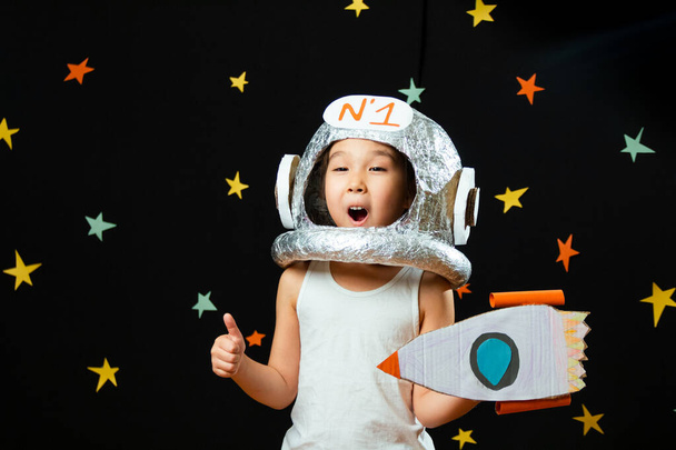 Porträt eines süßen kleinen Mädchens aus Aisan, das im Weltraum zu Hause ist, träumt und Astronaut spielt. Lustige Familienmomente - Foto, Bild