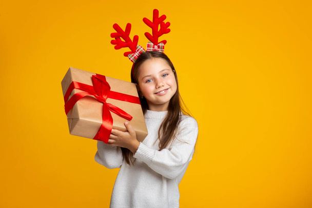 Gift from Santa Claus. Joyful girl holds present and listens to box - Photo, Image