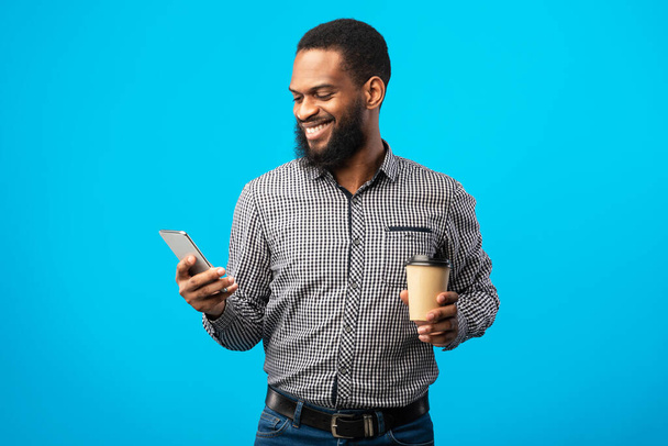 Smiling black man texting on the phone drinking coffee - Zdjęcie, obraz