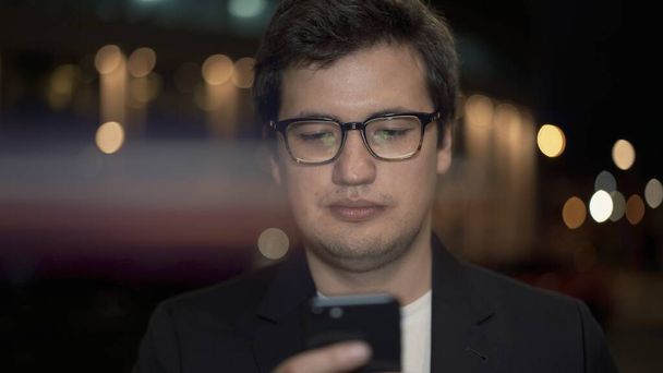 Businessman in eyeglasses scrolling the phone on background, lens flare - Foto, Imagem