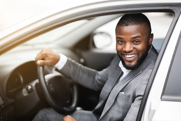 Веселый успешный черный бизнесмен смотрит в окно машины - Фото, изображение