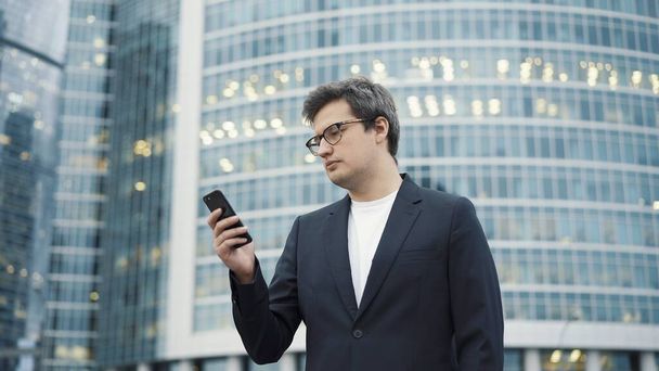 Man standing with a phone on background of business centre - Фото, изображение