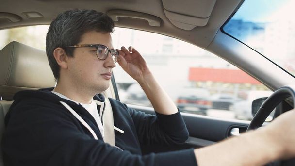 Man driving the car dressed in casual clothes adjusting eyeglasses - Fotó, kép