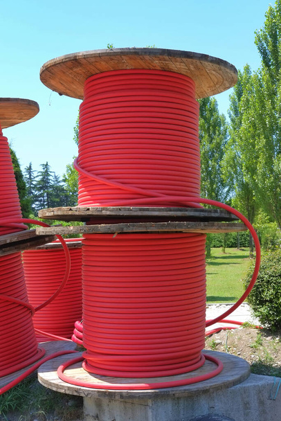 Bobines en bois avec câbles d'alimentation rouges dans le parc - Photo, image