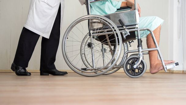 Orvos guggoló fogyatékkal élő ember több mint kerekesszék a padlón - Fotó, kép