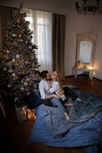 a couple in a bed in an apartment with a Christmas tree. Christmas - Valokuva, kuva