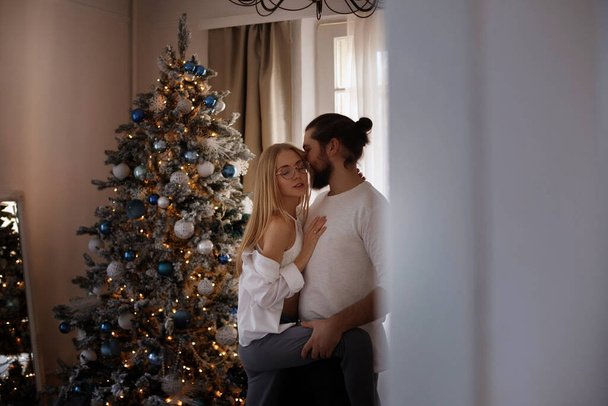 Noel ağacının yanındaki dairede öpüşen çift. - Fotoğraf, Görsel