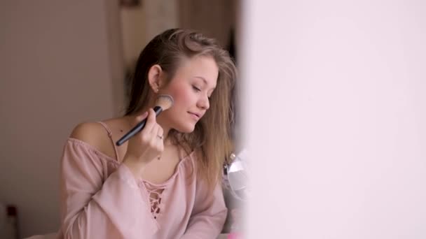 Kosmetyczna koncepcja młodej kobiety sprawia, że rumieniec na twarzy za pomocą szczotki do makijażu - Materiał filmowy, wideo