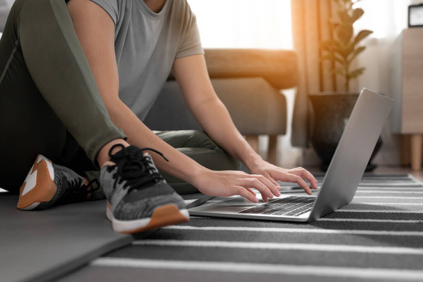 Молода спортивна жінка практикує тренування з ноутбуком в кімнаті
. - Фото, зображення