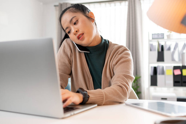 Frau telefoniert mit jemandem, während sie mit Laptop arbeitet - Foto, Bild