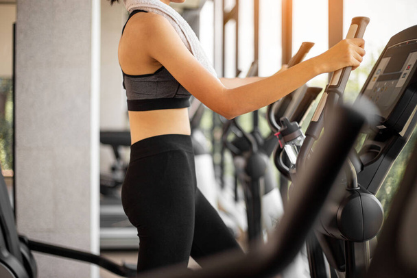 Young woman doing exercise cardio on elliptical trainer at gym. - Photo, Image