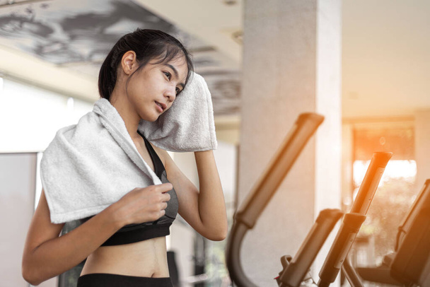 Mujer joven y cansada se limpia el sudor después de hacer ejercicio en el gimnasio. - Foto, Imagen