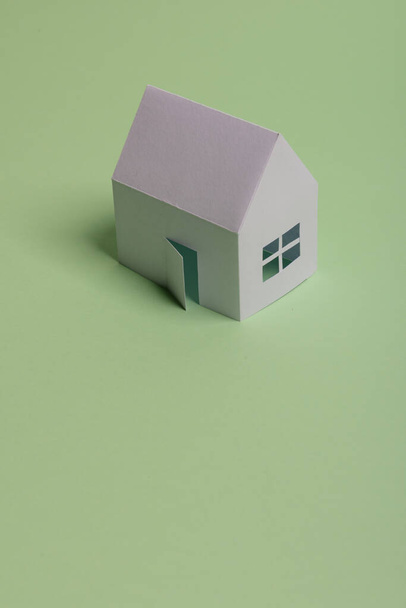 White family paper house in man hand on mint background paper. Minimalistic and simple concept, style. Copy space. Horizontal orientation - Photo, Image