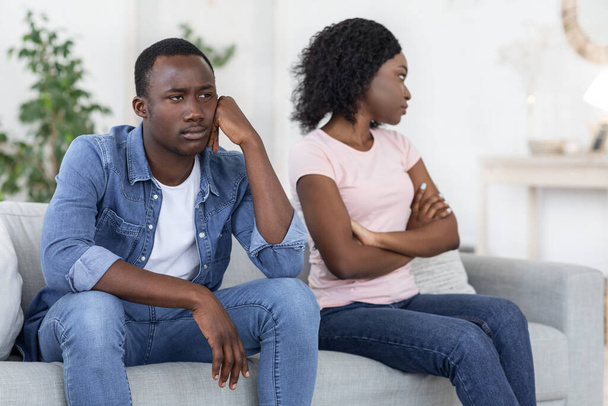 Upset black man and woman sitting on couch at home - Photo, Image