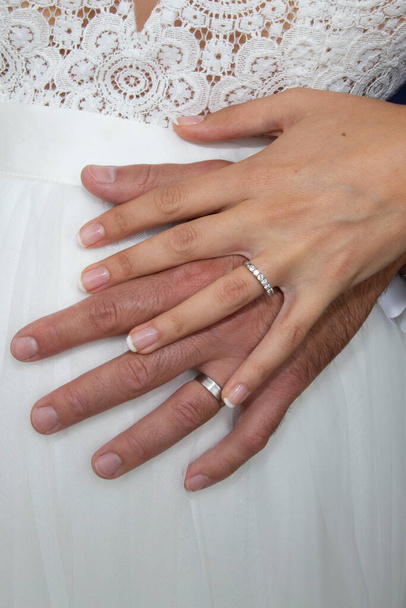 γαμήλιες βέρες στα χέρια γαμπρού νύφης σε λευκό φόντο φόρεμα - Φωτογραφία, εικόνα